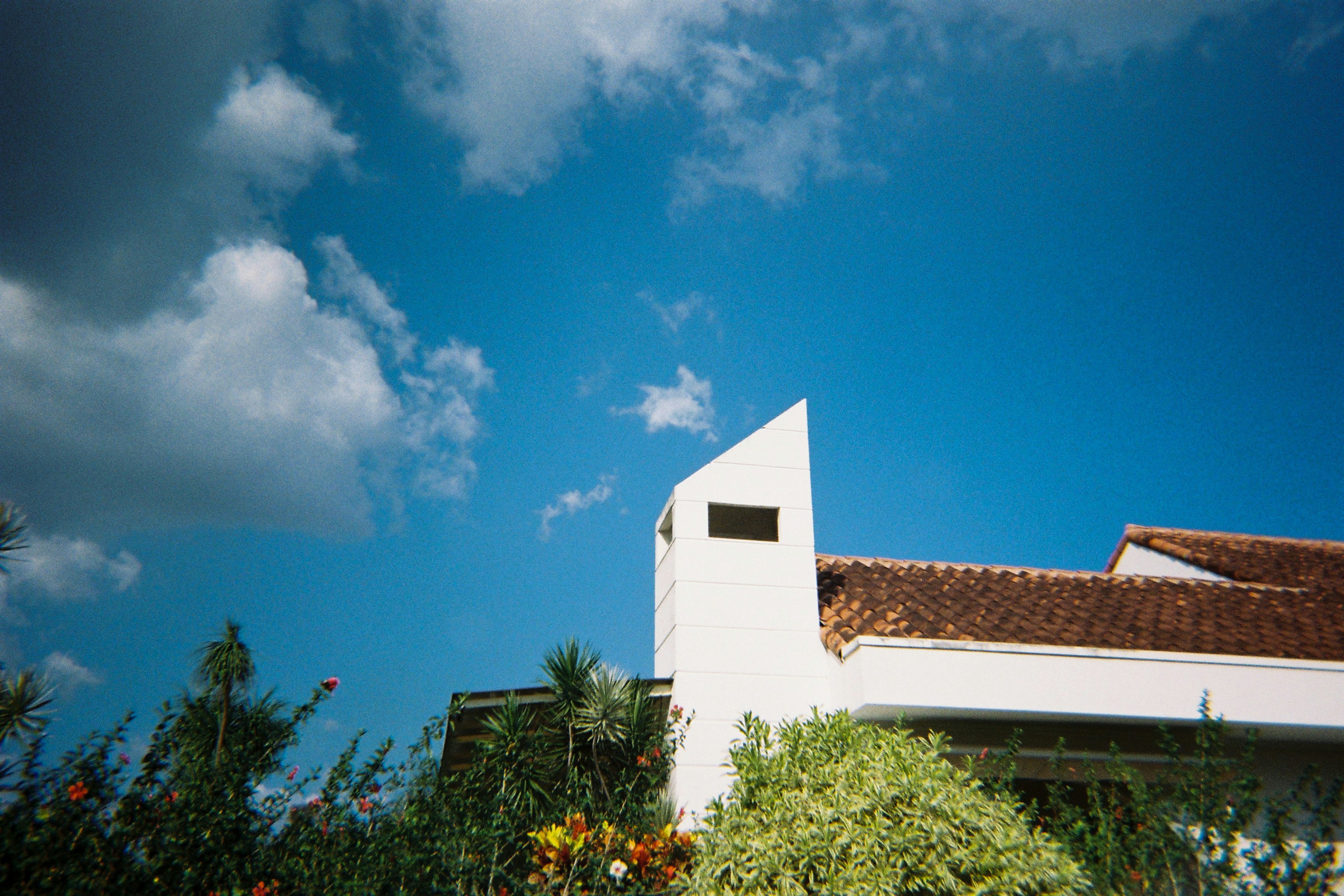 A white building with a red roof and a blue sky